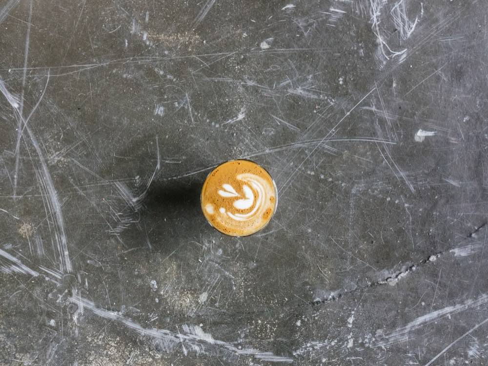 A flat white on a concrete table, seen from above