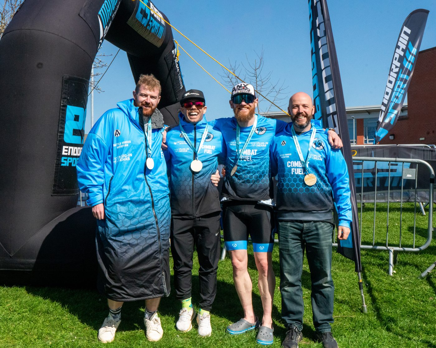 Four Team TC athletes in club kit, medals round their necks, at a race finish