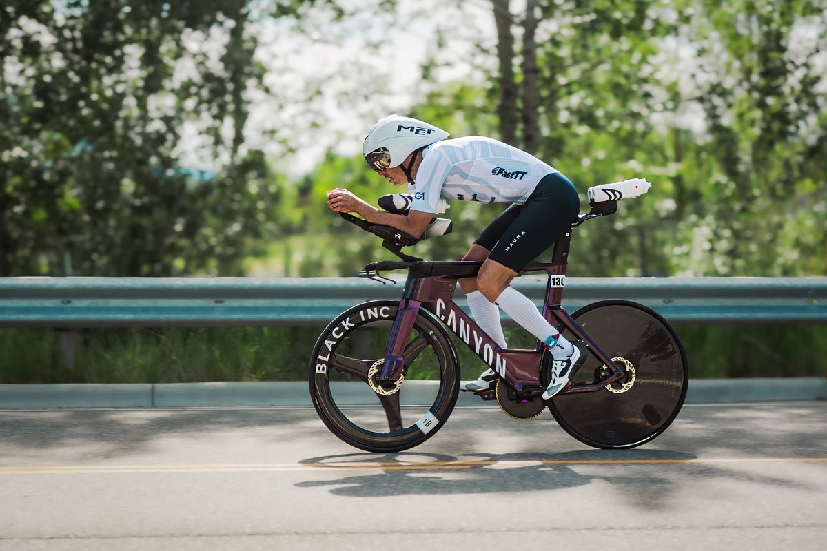 Triathlete tucked low on the aero bars of a disc-wheeled time trial bike