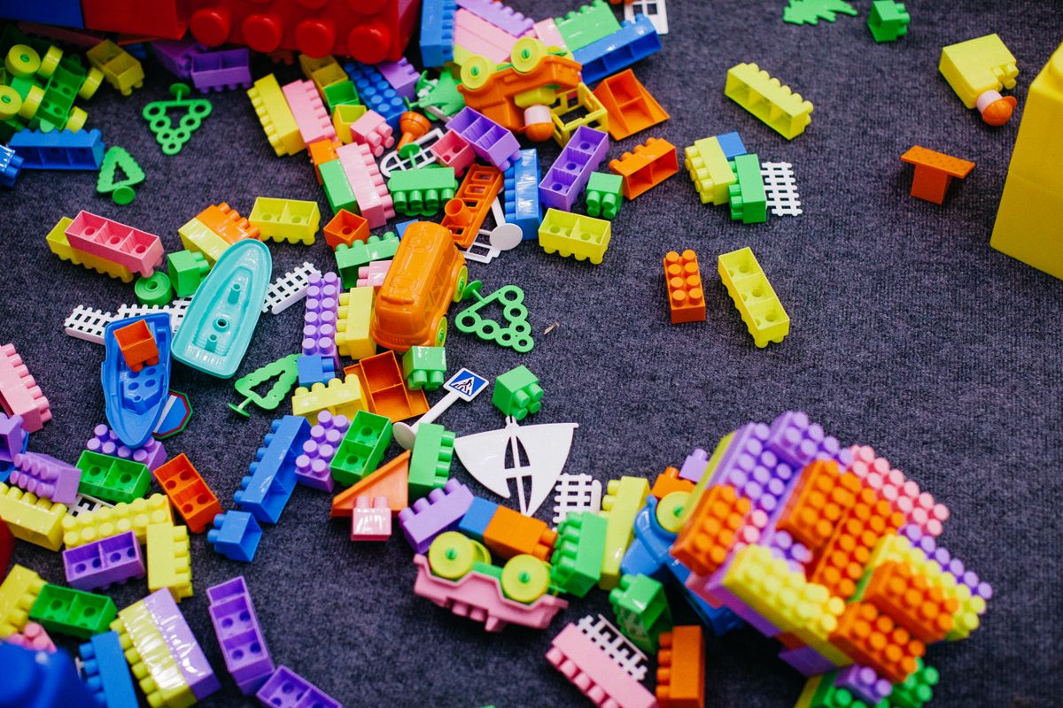 Colourful building bricks scattered across a carpet with a half-assembled model, a build left paused